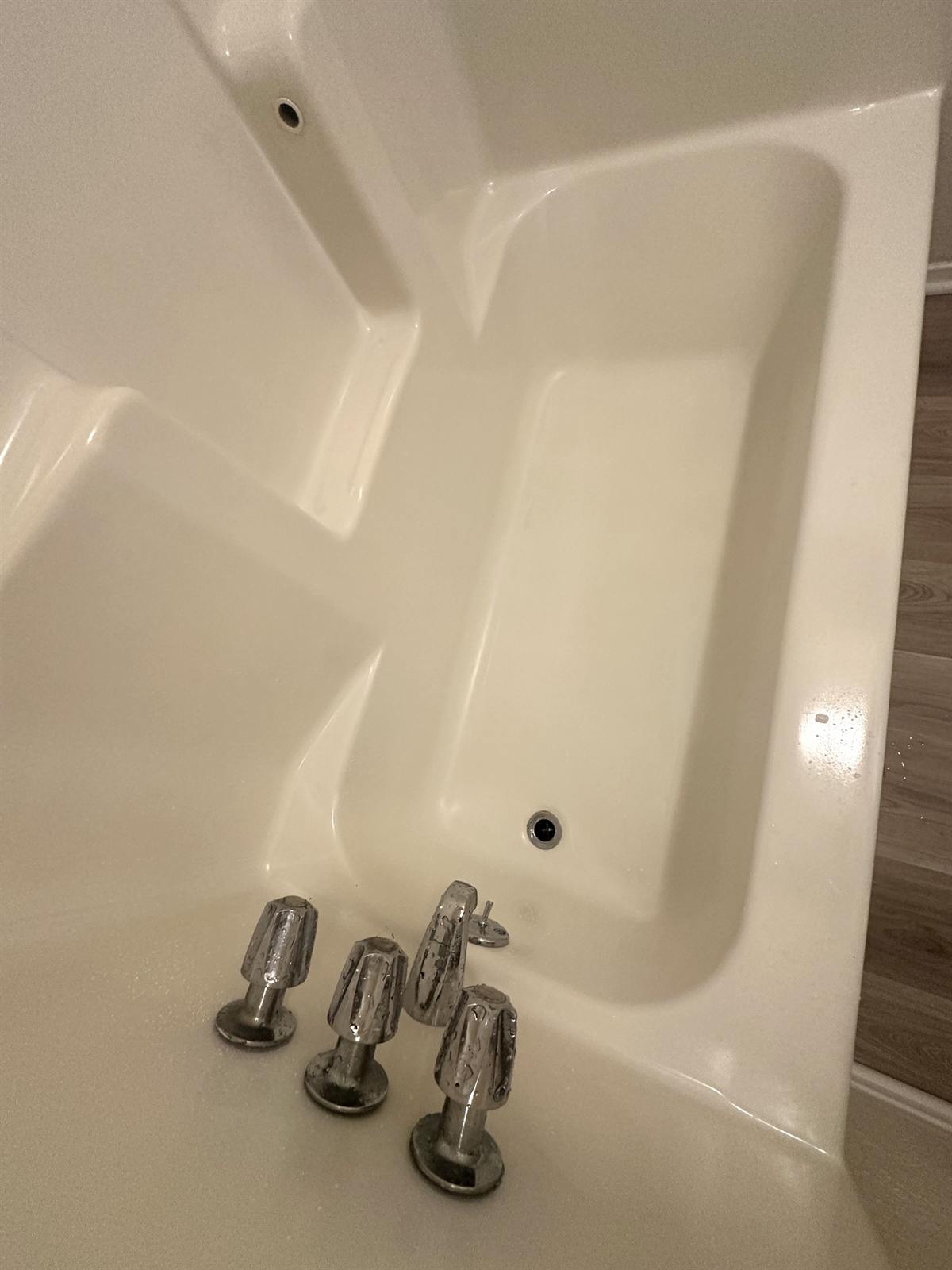 After one-day bathtub refinishing in Austin with repaired drain area and smooth white finish