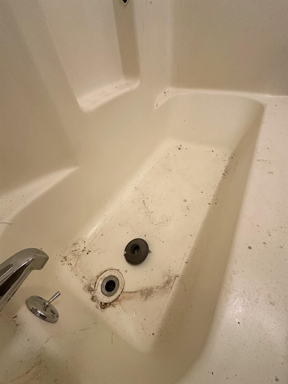 Before bathtub crack repair in Austin showing drain-area damage before resurfacing