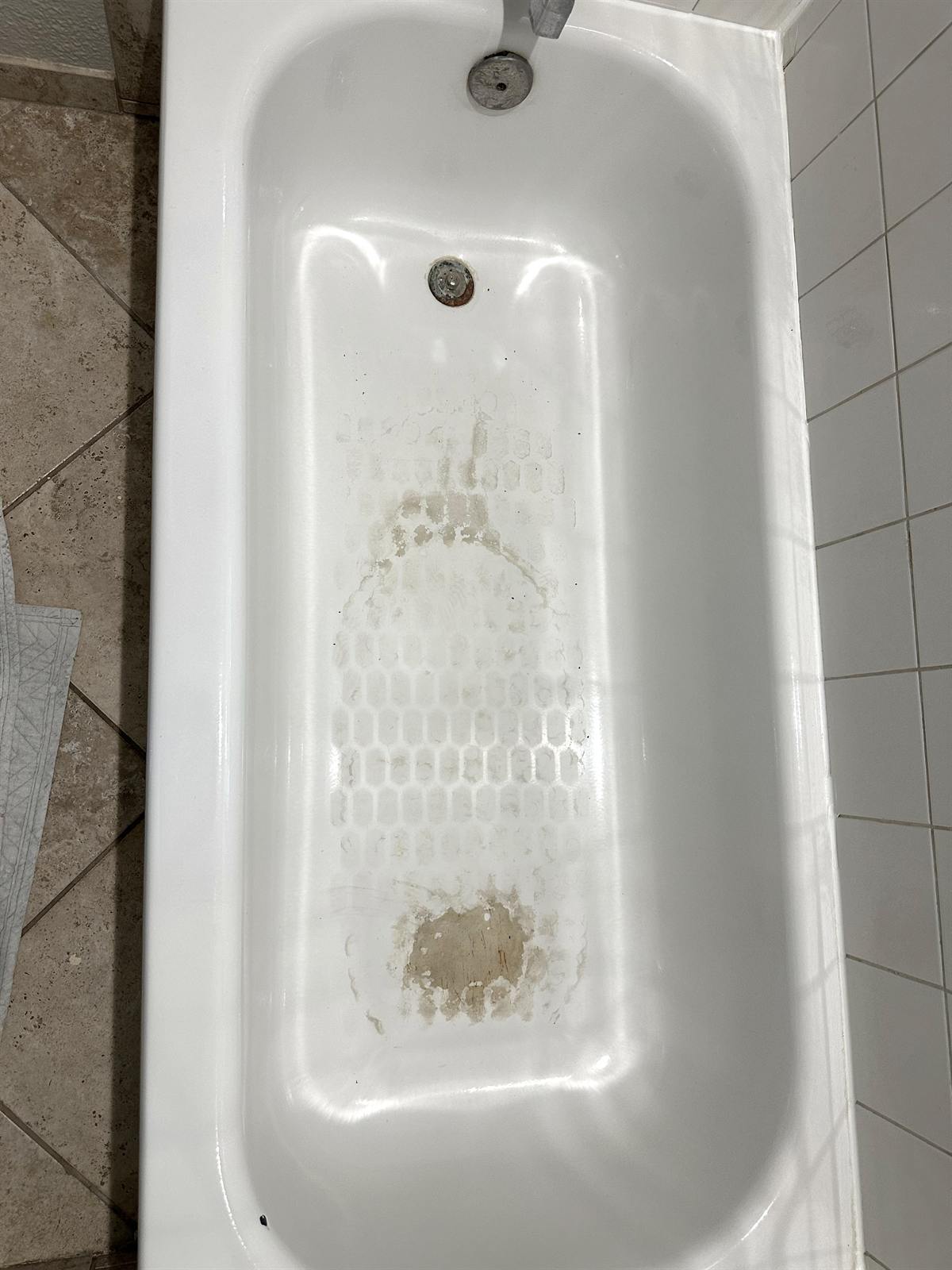 Before bathtub resurfacing with worn floor coating and heavy staining
