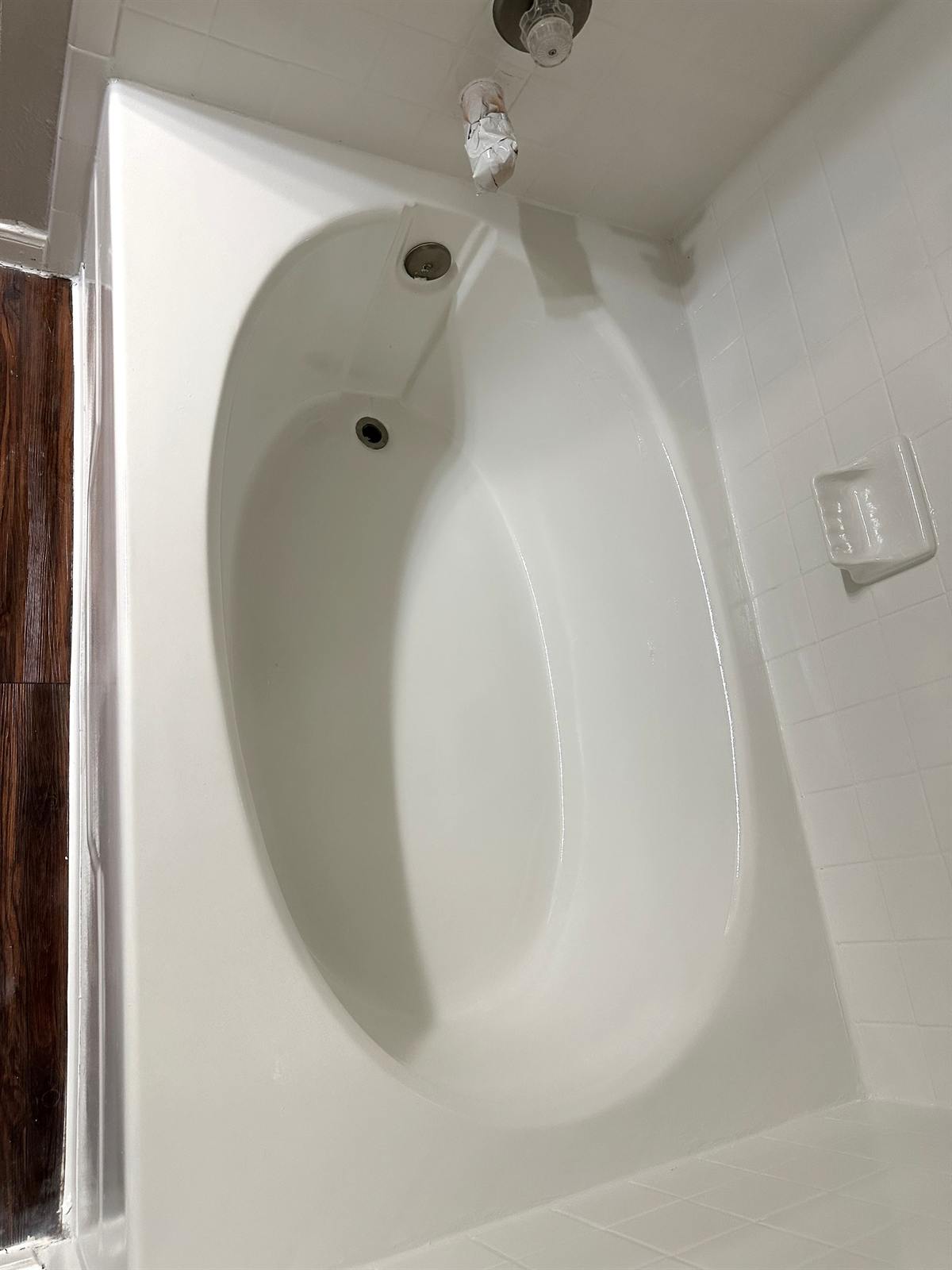 After one-day tub refinishing with glossy white finish on oval bathtub