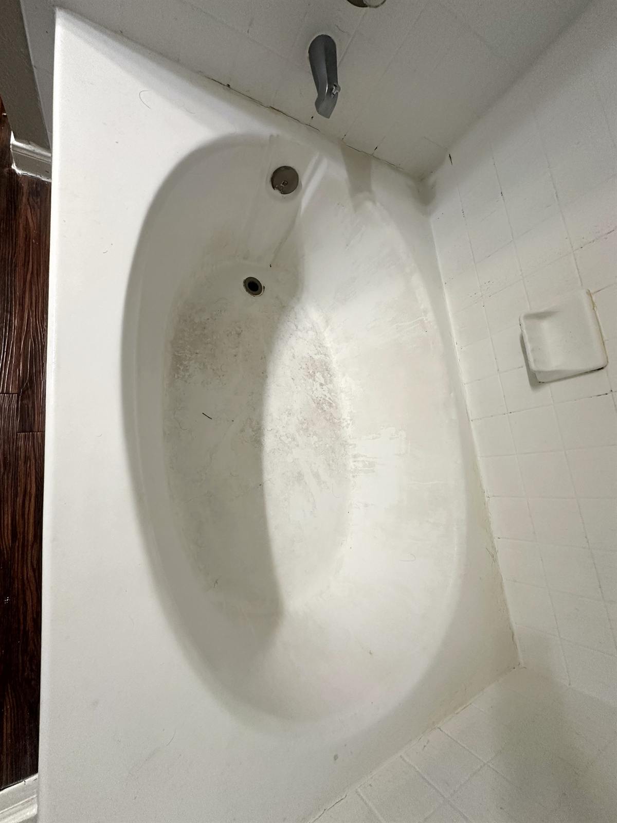 Before bathtub refinishing showing worn oval tub surface and discoloration